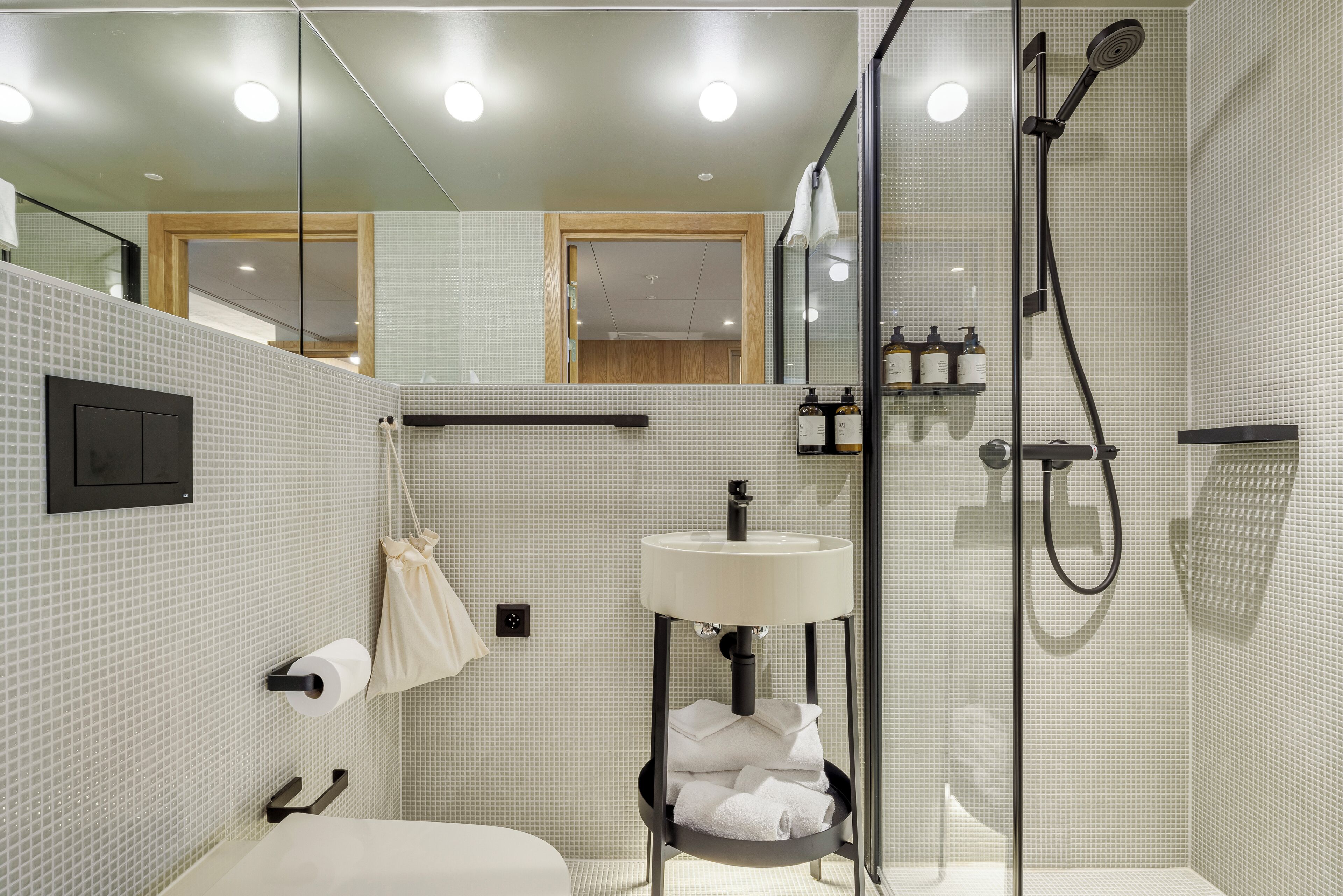 Un baño moderno con ducha acristalada, lavamanos con toallero y retrete.