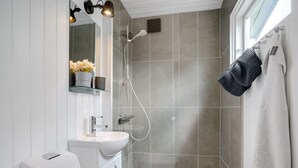 A modern bathroom with a glass shower enclosure, a white sink, and a towel rack with towels. - "Francis" - 300m from the sea by Interhome (Rødvig Stevns)