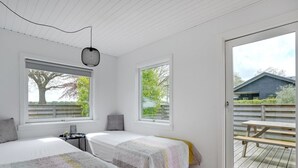 A bedroom with two beds, a desk, and a large window with a view of a tree and a building. - "Francis" - 300m from the sea by Interhome (Rødvig Stevns)
