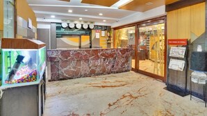 Eine Lobby mit einem Marmor-Rezeptionsschalter, einem Aquarium und Wanduhren.