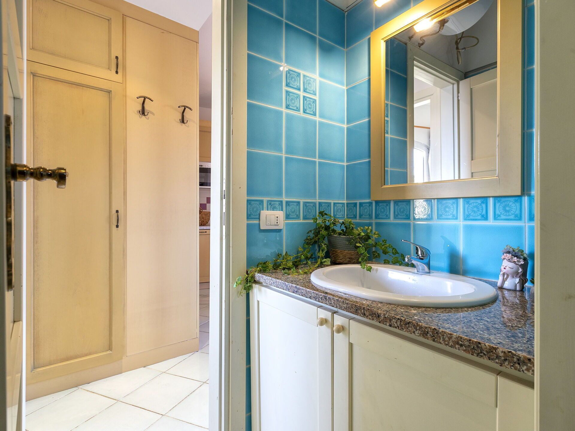 A bathroom with a sink, mirror, and blue tiles.