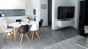 Un salon moderne comprenant un coin repas, une cuisine et un téléviseur à écran plat.