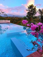 Una piscina al aire libre, sombrillas, sillones reclinables de piscina