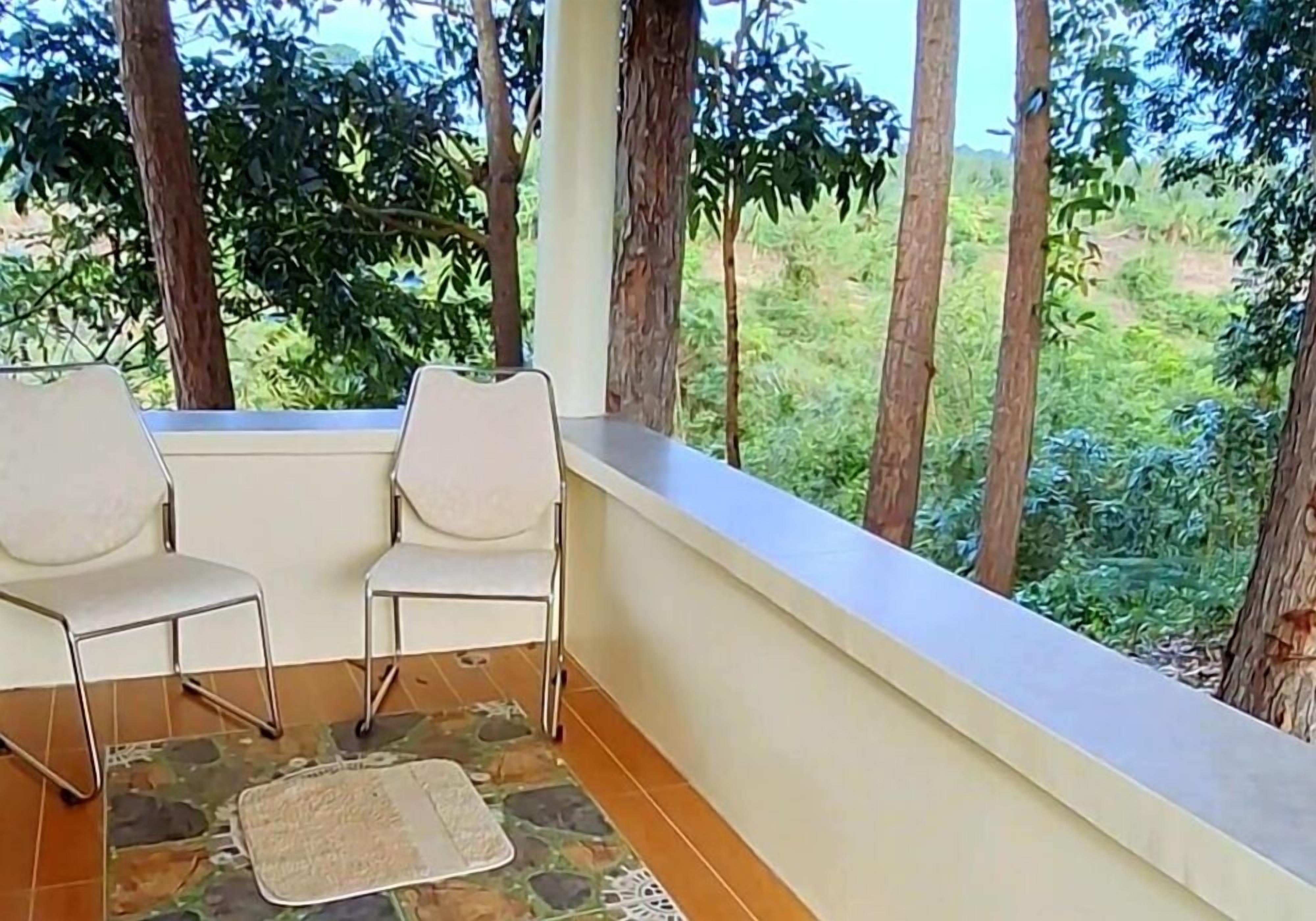 A balcony with two white chairs and a patterned rug.
