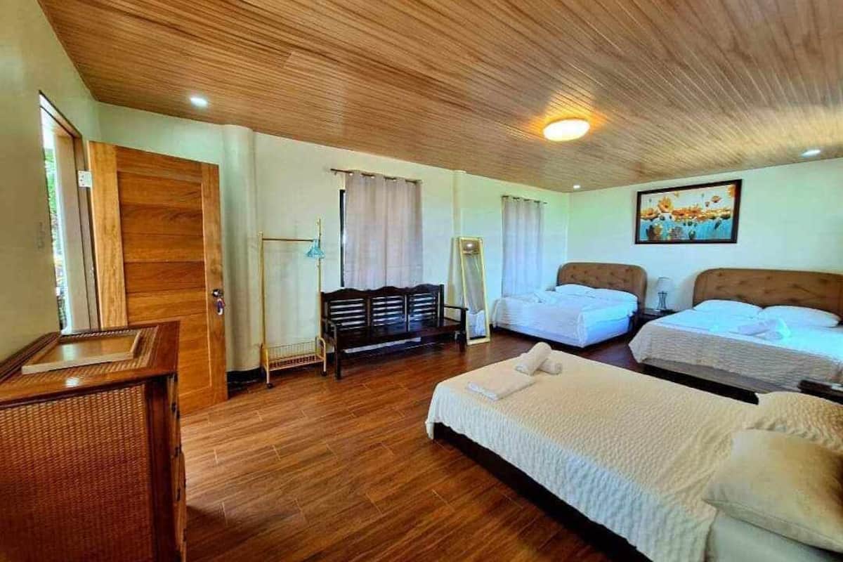 A hotel room with wooden flooring, two beds, a desk, and a chair.