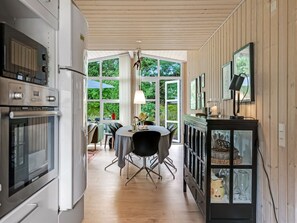 Een moderne keuken met een eetgedeelte, houten vloeren en grote ramen.