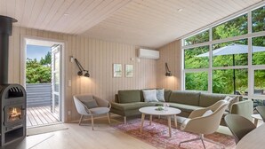 A cozy living room with a fireplace, a sofa, a coffee table, and a large window with a view of greenery. - "Akkar" - 1.8km from the sea by Interhome (Blåvand)