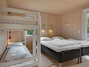Une chambre avec un lit superposé, un lit double et une fenêtre donnant sur un paysage verdoyant.