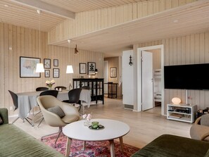Un salon moderne comprenant un coin repas, des murs en bois, un téléviseur à écran plat et un espace salon confortable.