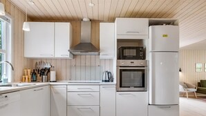 A modern kitchen with white cabinetry, a built-in oven, microwave, and a large refrigerator. - "Akkar" - 1.8km from the sea by Interhome (Blåvand)