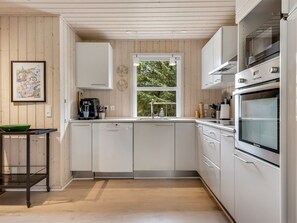 Een moderne keuken met witte kasten, een vaatwasser, een koffieapparaat en een groot raam.