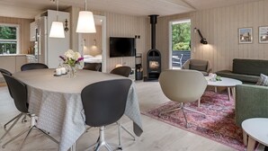 A modern interior with a dining area, kitchen, and living space, featuring wooden walls, a fireplace, and contemporary furniture. - "Akkar" - 1.8km from the sea by Interhome (Blåvand)