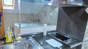 Uma cozinha moderna com uma pia de aço inoxidável, forno embutido e janela com vista para uma varanda.