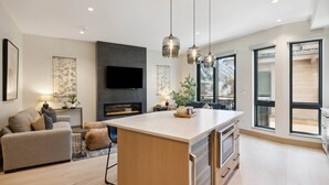 A modern kitchen with a central island, a built-in oven, and a large window. - One Riverfront Condo 108 (Avon)