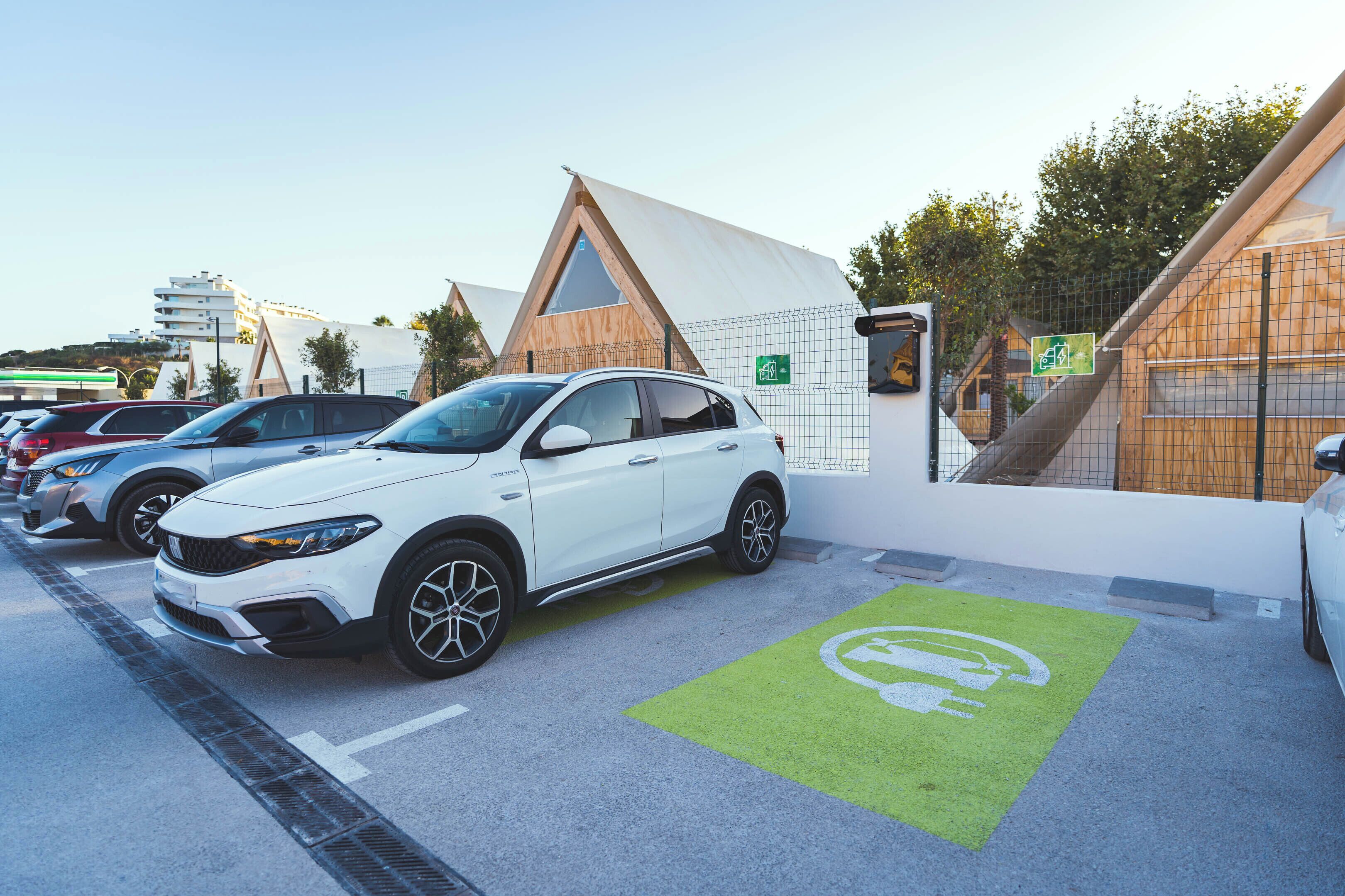 A parking area with electric vehicle charging stations, marked by green floor decals.