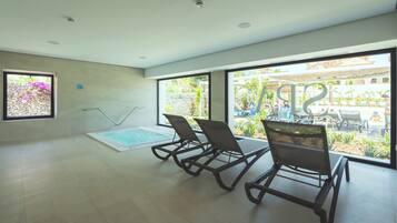 Amplio espacio interior con piscina, ventanas grandes y vista a una zona de piscina exterior.