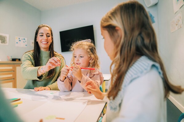 A room with a table where three people are engaged in an activity, possibly a craft or educational session. - Costa del Sol Glamping Village Fuengirola (Fuengirola)