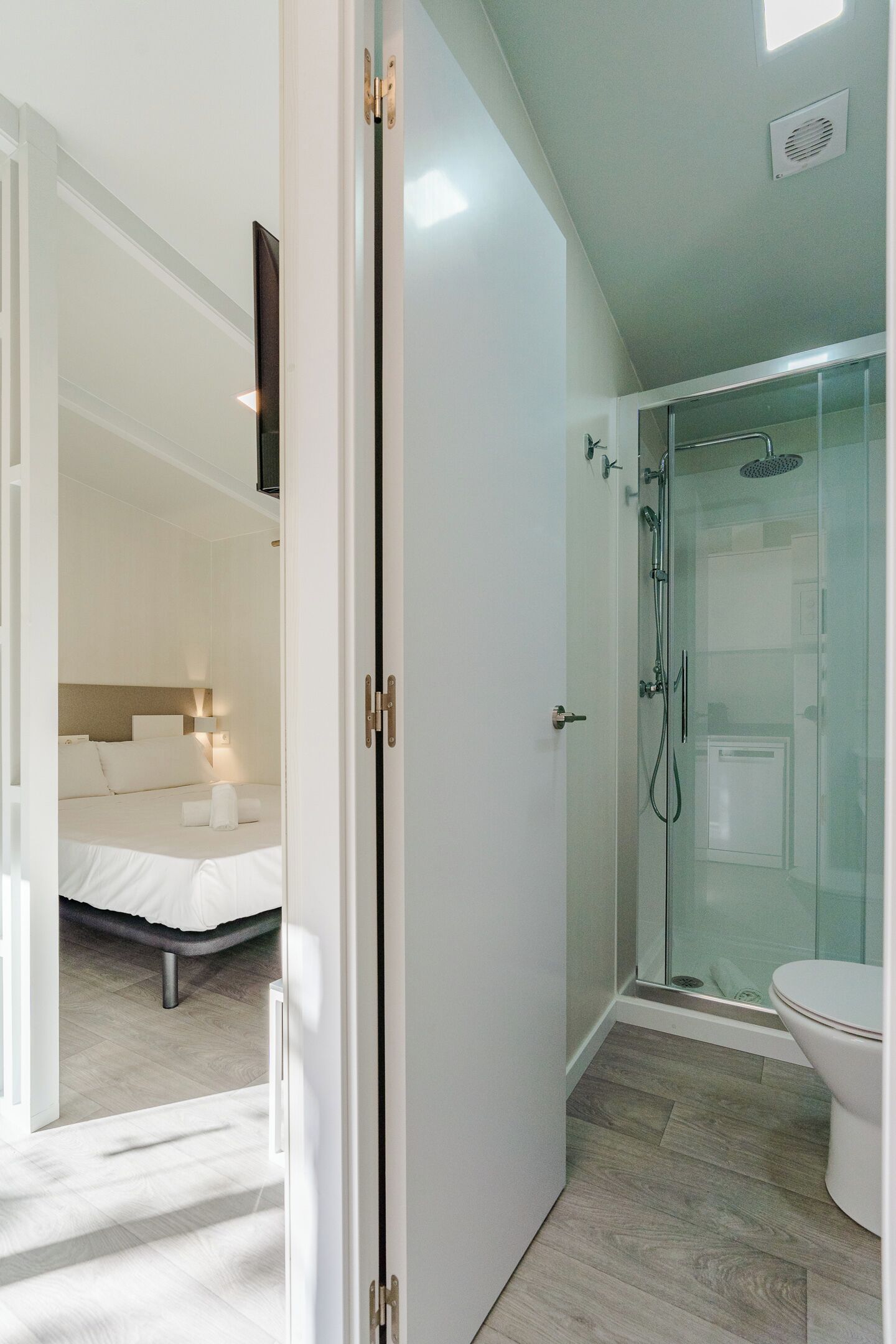 A modern bathroom with a glass-enclosed shower, a toilet, and a visible showerhead.