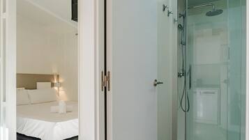 Et moderne badeværelse med en glasafskærmet brusekabine, toilet og et synligt brusehoved.