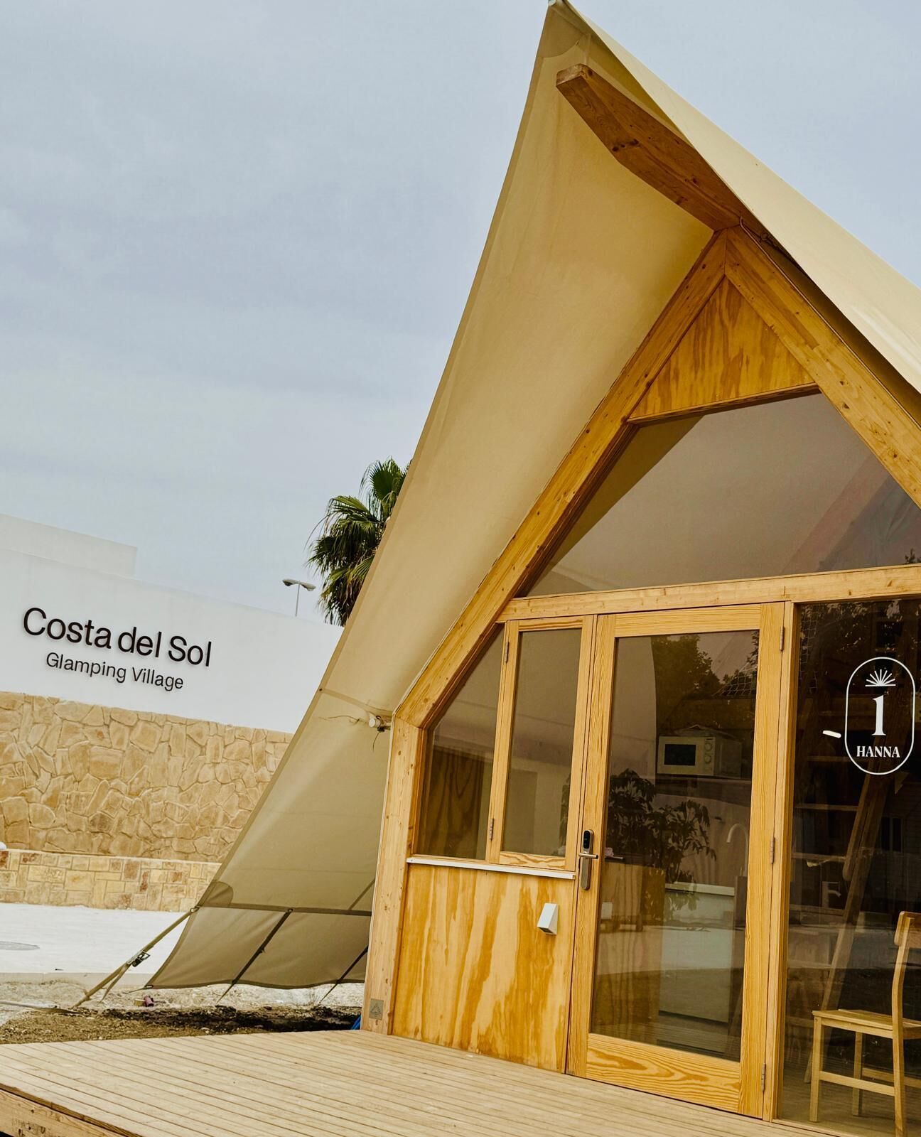 Eine Holzhütte mit einer großen Glastür und einem geneigten Dach, gelegen im Costa del Sol Glamping Village.