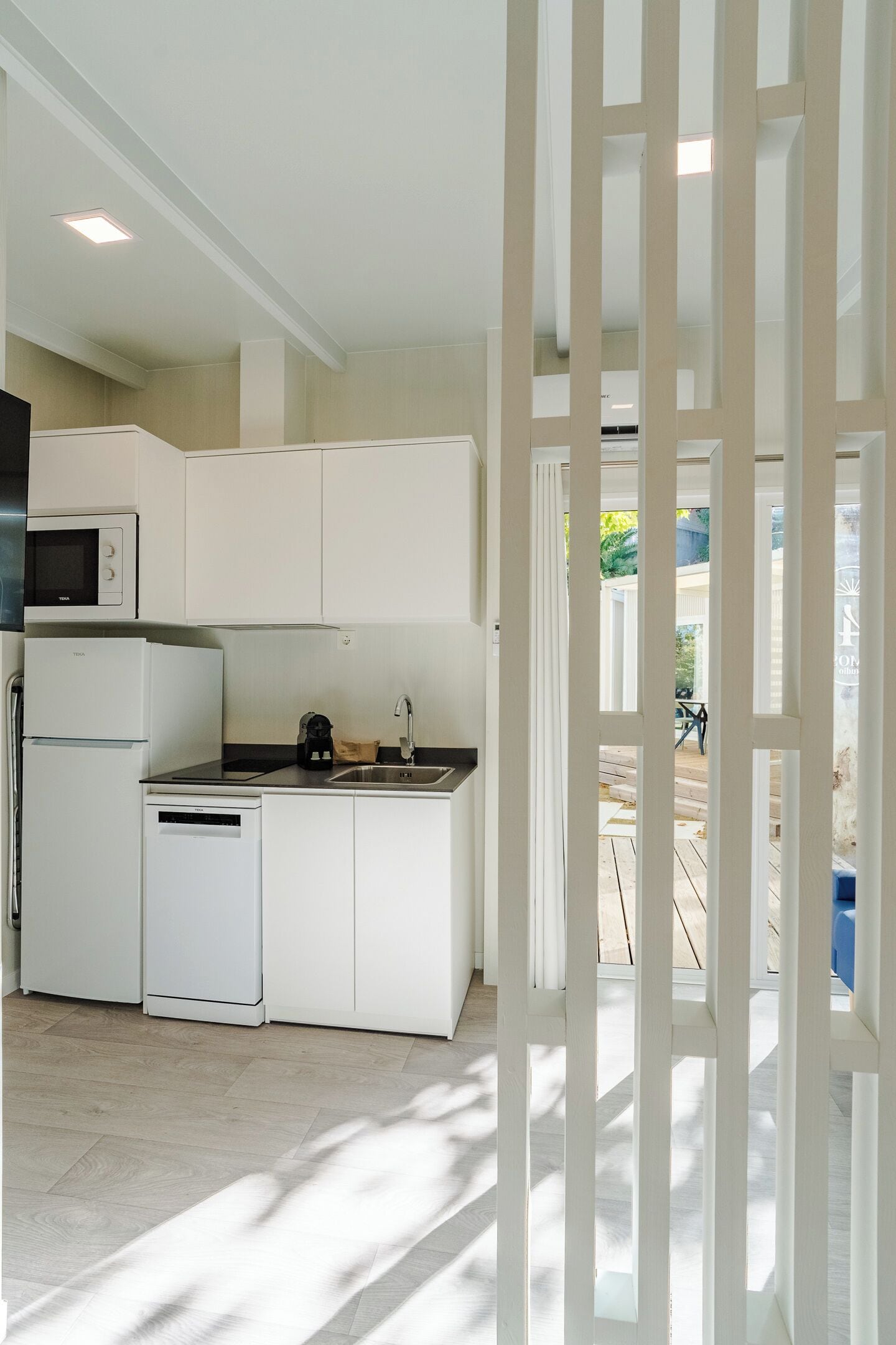 Una cocina moderna con armarios blancos, microondas integrado, lavavajillas y pileta.