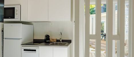 Una cocina moderna con armarios blancos, microondas integrado, lavavajillas y pileta.