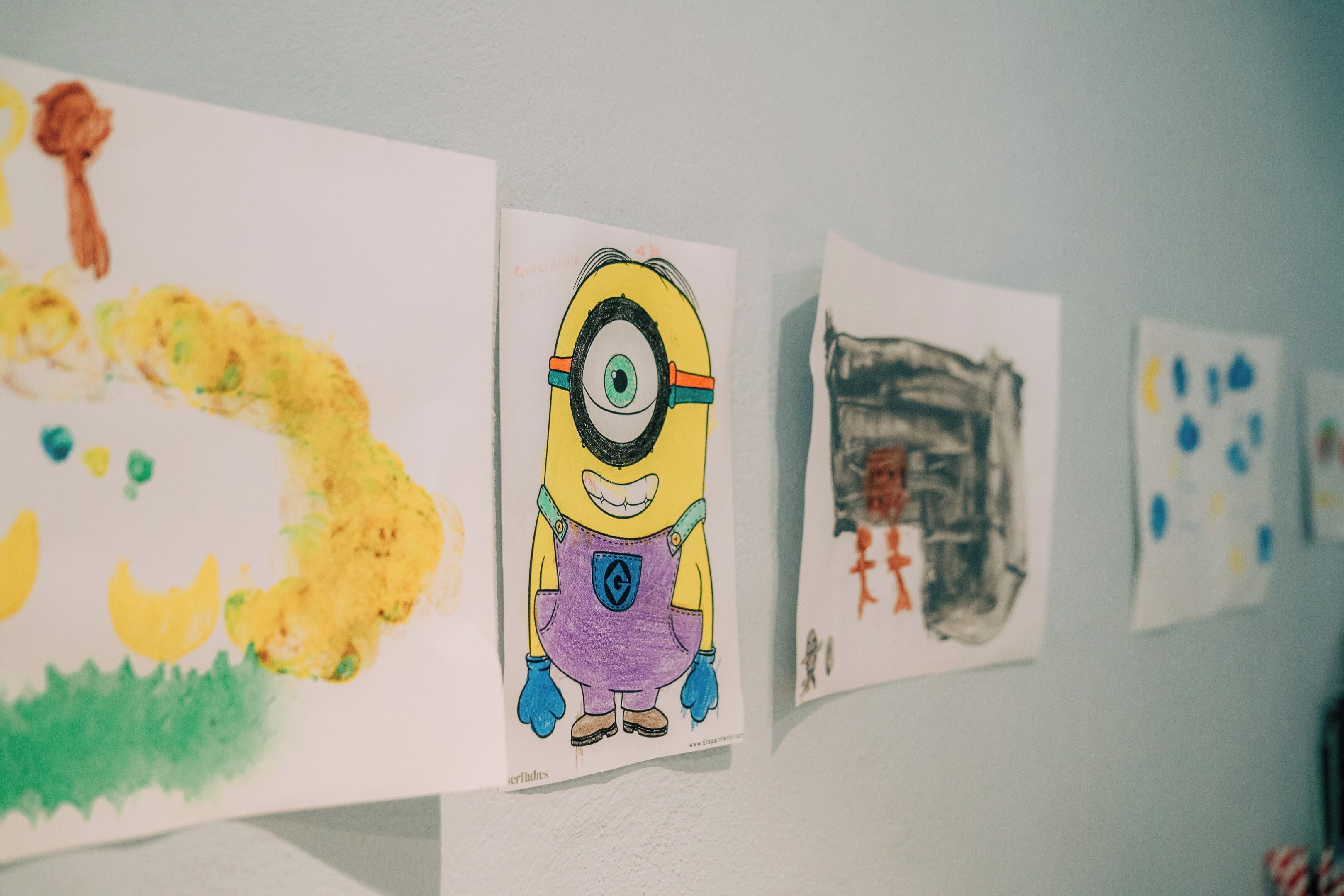 Een muur met kindertekeningen, waaronder een Minion personage.