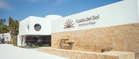A modern building with a stone facade and a sign reading "Costa del Sol Glamping Village."