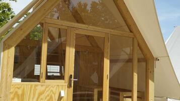 A wooden structure with a pitched roof and large glass doors, likely a temporary accommodation or event space.