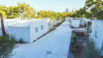 A row of white mobile homes with a paved driveway and trees in the background.