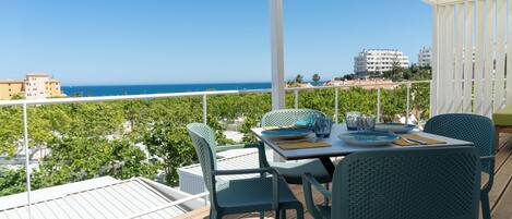 Un balcon avec une table dressée pour le dîner, offrant une vue sur la plage et le paysage urbain.