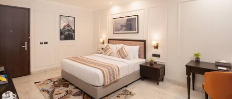 A modern bedroom with a large bed, bedside tables, a desk, and a chair.