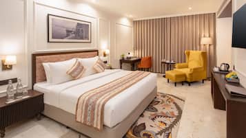 A hotel room with a large bed, a desk, a chair, and a television.