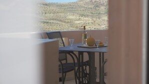 A balcony with a table set for two, a bottle, and glasses.