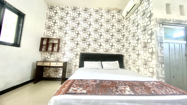 Ein Schlafzimmer mit Bett, Nachttisch, Kommode und einer Wand mit Muster.