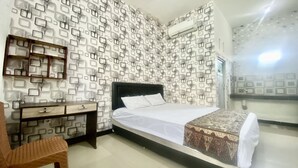 Ein Schlafzimmer mit einem Bett, einem Holzstuhl, einem Schreibtisch mit Schubladen und einer Wand mit Muster.