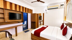 Ein Hotelzimmer mit Bett, Fernseher, Schreibtisch und Badezimmer.