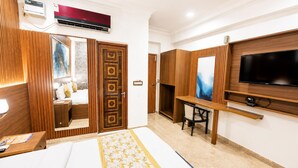 A hotel room with a bed, a desk, a TV, and a wardrobe. - Atlas Inn Near IGI Airport (New delhi)