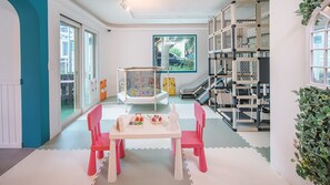 Uma sala de jogos com um cercadinho, um escorrega e uma estrutura de escalada.
