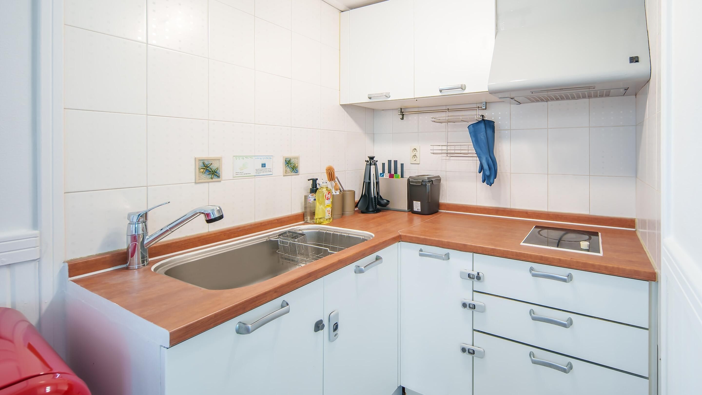 Une cuisine avec des armoires blanches, un plan de travail en bois, un évier en acier inoxydable et une serviette bleue suspendue à un porte-serviettes.