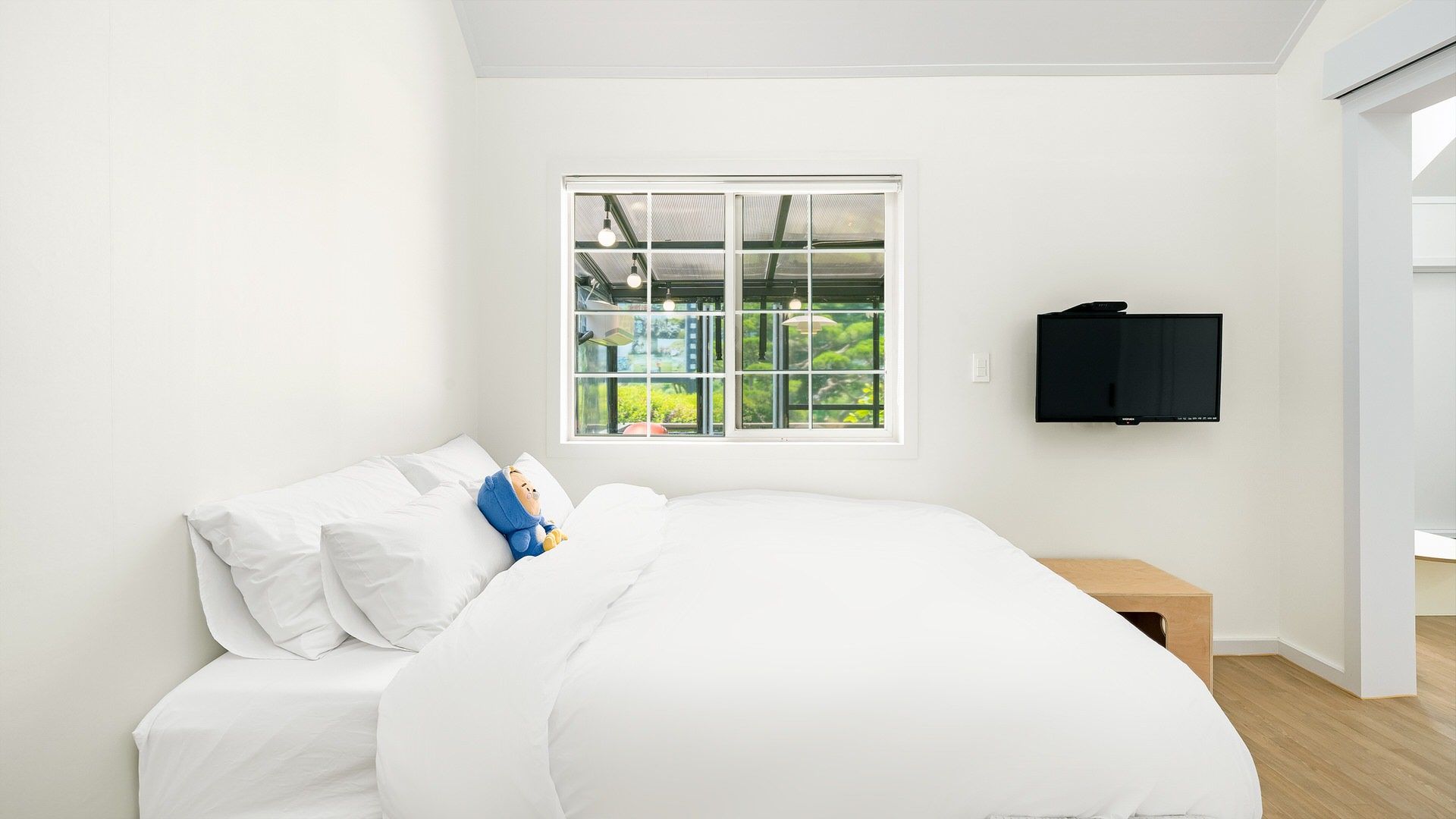 A bedroom with a bed, a window, a TV, and a nightstand.