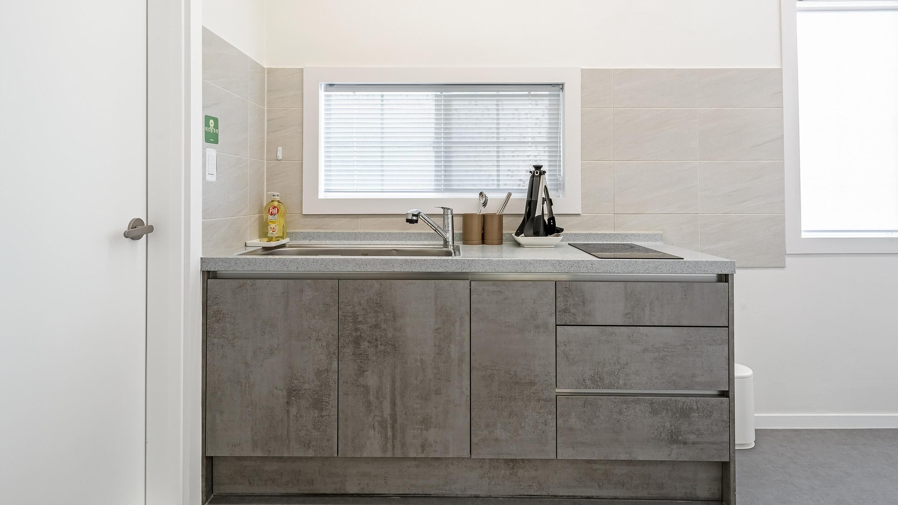 Una cocina moderna con un lavamanos doble, una ventana con persianas y una puerta con picaporte.