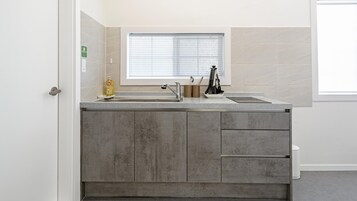 Una cocina moderna con un lavamanos doble, una ventana con persianas y una puerta con picaporte.