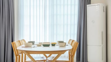 Una mesa de comedor con sillas, tazones y un refrigerador blanco.