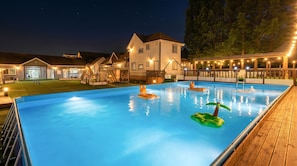 A swimming pool with inflatable toys, a wooden deck, and a building with multiple windows and a porch. - Gapyeong Dangdangi Pet Pension Green (Gapyeong)