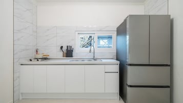 A kitchen with white cabinets, a stainless steel refrigerator, a window with a view, and a gas stove.