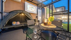 Un espace extérieur aménagé avec une tente, une table, des chaises, une lanterne et un verre de vin.