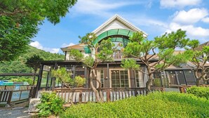 Une maison de style japonais traditionnel, dotée d’un toit végétalisé, de grandes fenêtres et d’une clôture en bois.