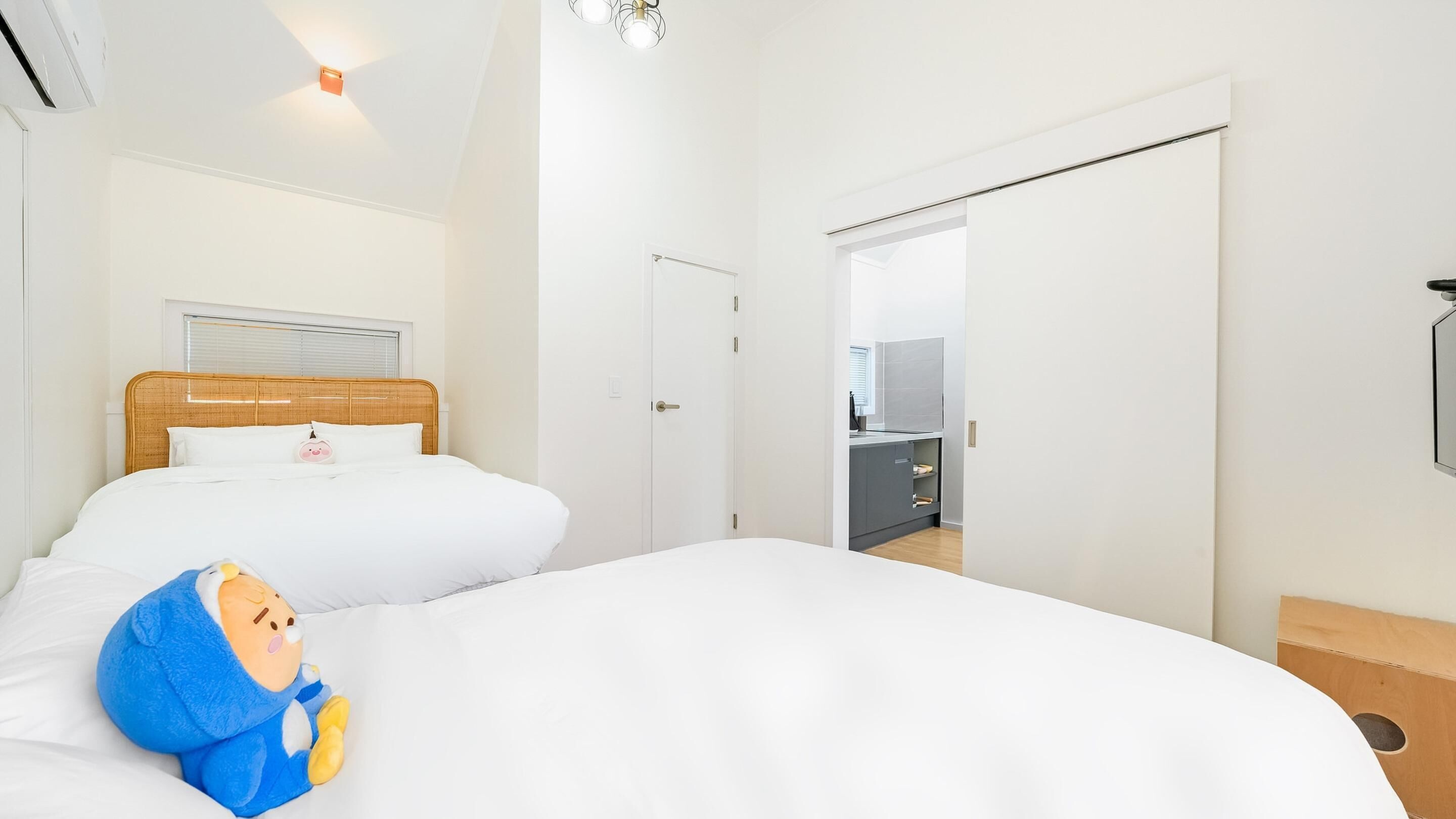 A hotel room with a large bed, a bedside table, a wardrobe, and a view of the kitchen.