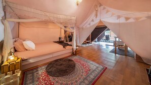 Une chambre à coucher avec un lit à baldaquin, un tapis à motifs et une vue sur l’extérieur.